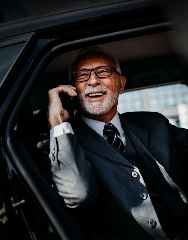 Smiling man talking on phone in car.